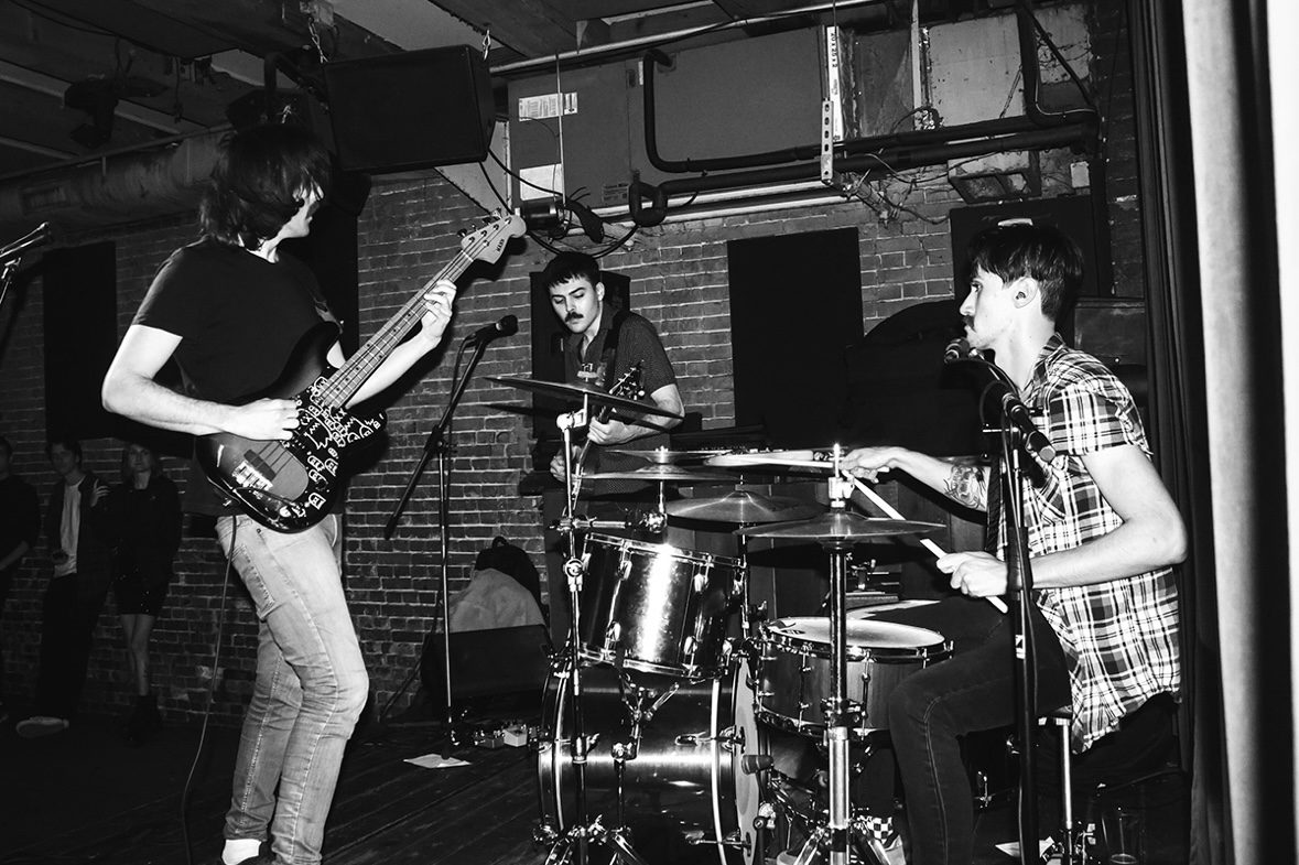 Caught Feelings live — black and white photo of three musicians performing on stage