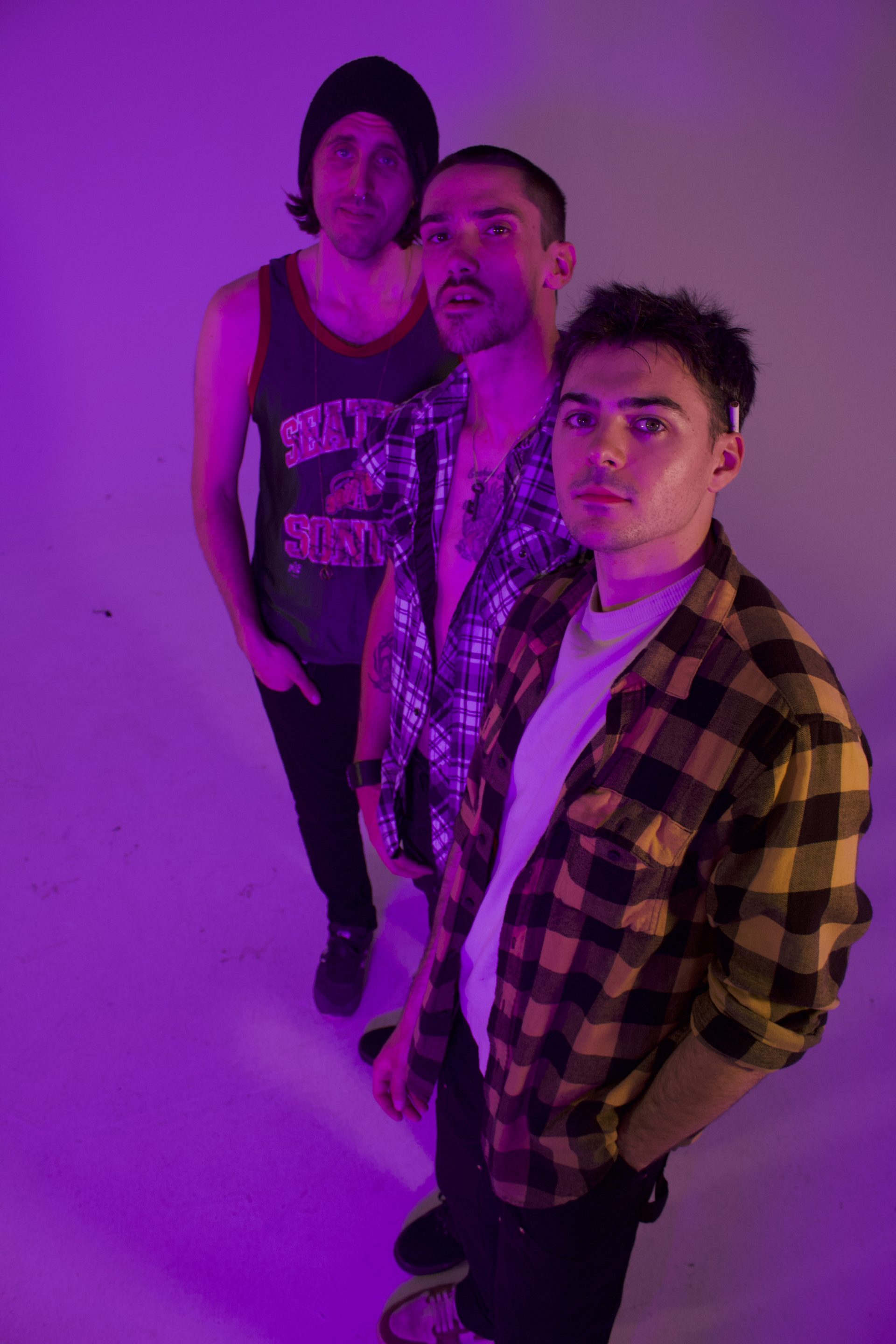 Caught Feelings — three band members posing in purple light