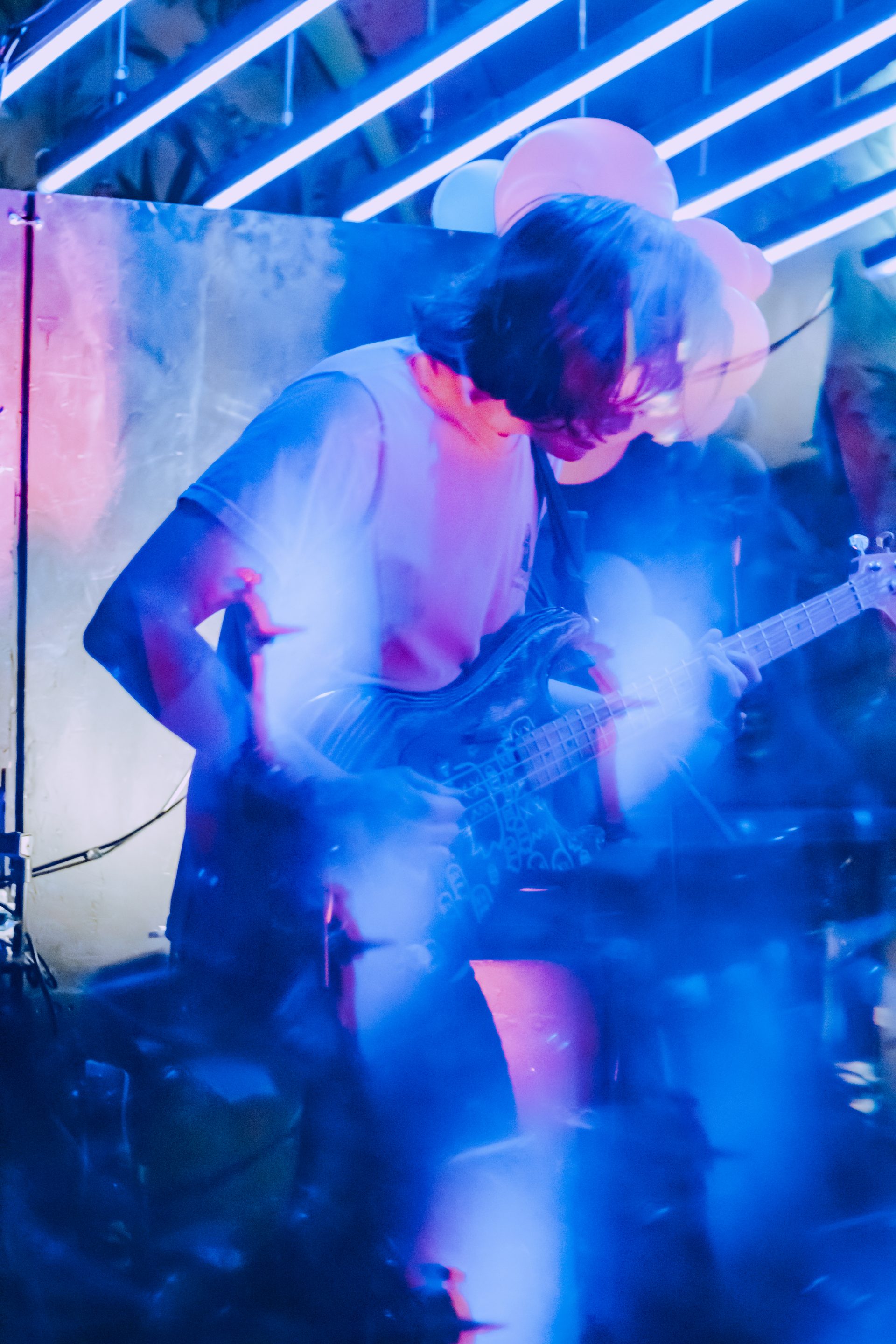 Caught Feelings bassist performing under blue neon lights with haze and motion blur